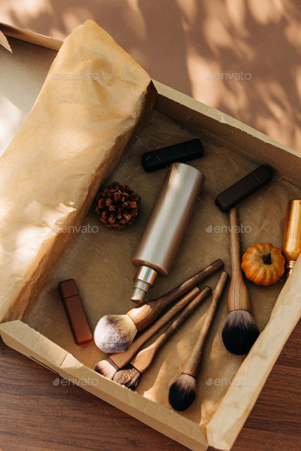 Brushes, lipsticks and other cosmetics in a box with decorated pumkins
