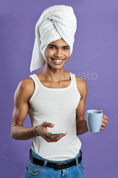 Portrait of young man looking camera with mobile and coffee cup. Smiling latin american transgender