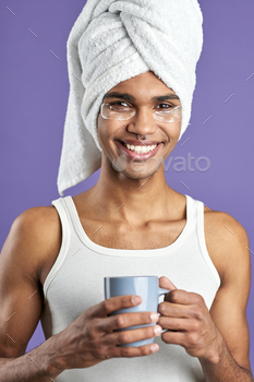 Young man with eye patches in towel on head and cup of tea portrait