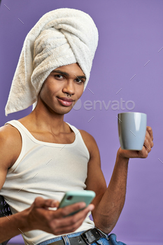 Young man in towel on head looks to camera portrait. Smiling latino transgender male with