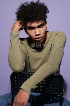 Close-up portrait of afroamerican male looking camera on purple background. Young transgender man