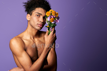 Nacked hispanic male with flowers in hand posing on purple background. Transgender man nude torso