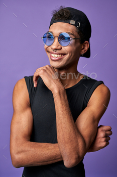 Portrait of cheerful transgender male in black t-shirt, blue sunglasses. Latin american trans