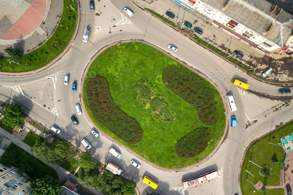 Top down aerial view of busy street roundabout intersection with moving cars traffic.