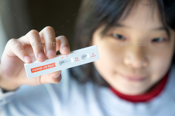 Little girl is showing negative results on rapid antigen test kit for covid-19.