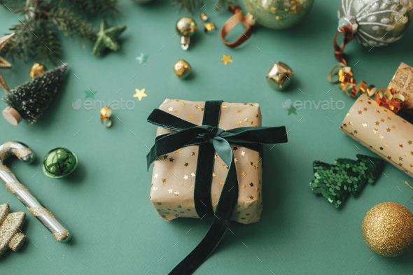 Stylish christmas gift wrapped in gold paper and green ribbon, festive  decorations on green Stock Photo by Sonyachny