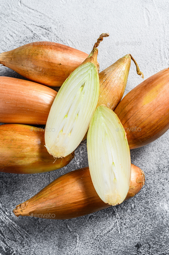 Yellow shallot onions, cut in two halves. Gray background. Top view