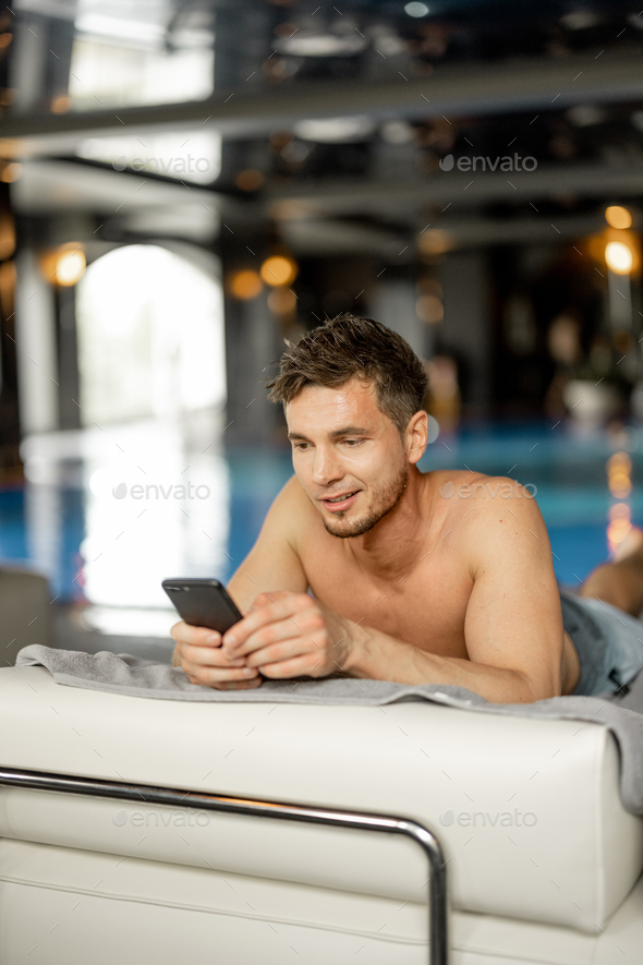 Man rests with phone by the swimming pool indoors at spa resort Stock ...