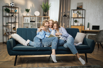 Happy loving family at home. Pretty young caucasian mother reading a book to her daughters