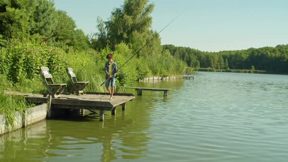 skillful-arab-teenage-boy-with-fishing-rod-enjoying-fishing-from-jetty