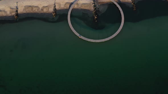 Drone Shot Revealing Infinite Bridge and a Vast Lush Field Against Sunny Sky alt