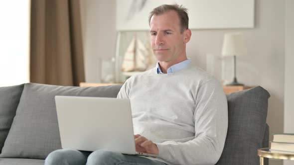 Professional Middle Aged Businessman Using Laptop on Sofa  alt