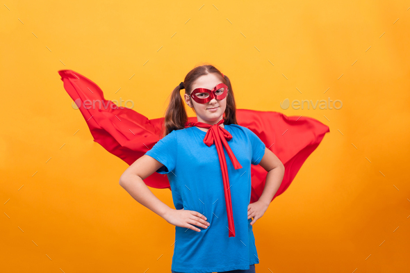 Little girl in super hero costume ready to save the world from bad guys over yellow background