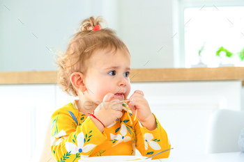 children in the kitchen at the table eat pasta.