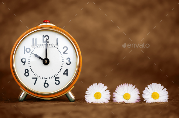 Retro alarm clock and flowers, spring forward, daylight saving time background