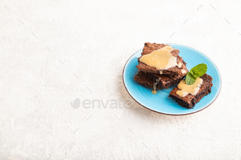 Chocolate brownie with caramel sauce on gray concrete, side view, copy space.