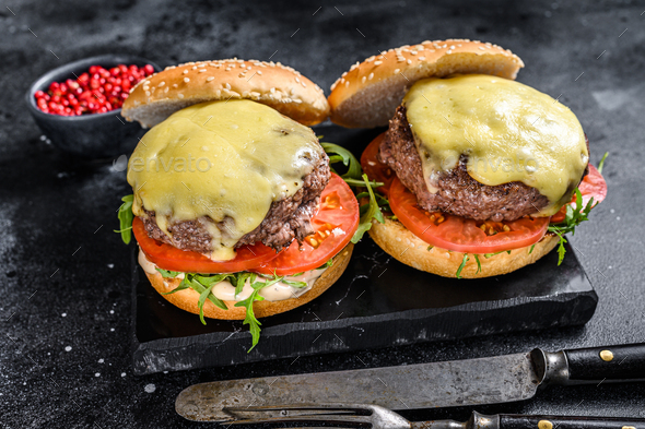 Grilled homemade burgers with beef, tomato, cheese, cucumber and lettuce. Black background. Top view