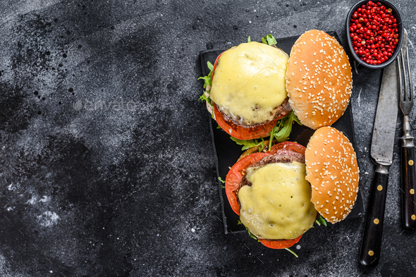 Grilled homemade burgers with beef, tomato, cheese, cucumber and lettuce. Black background