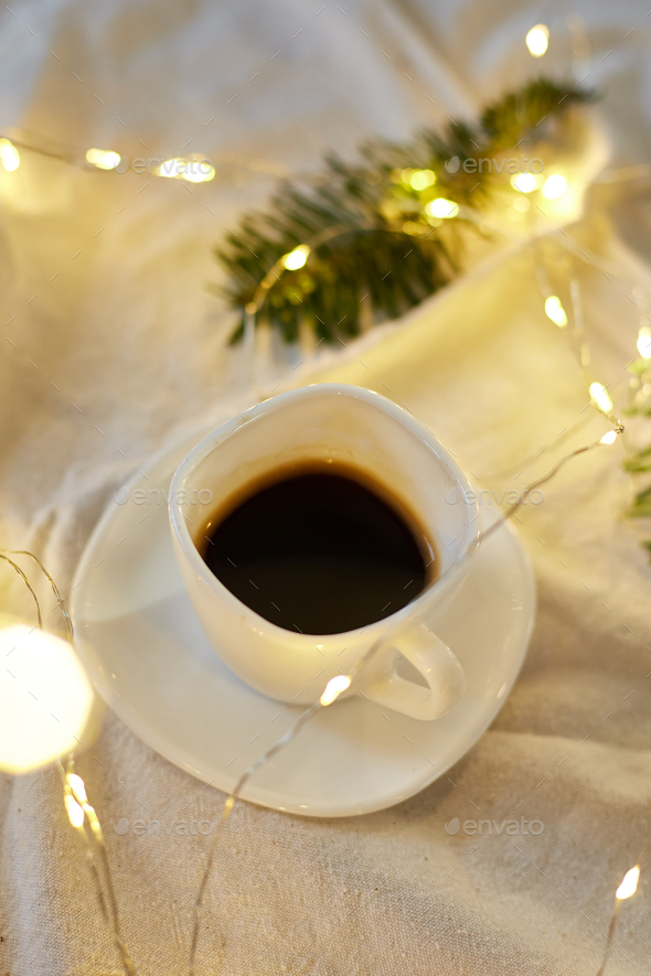 Cup of coffee in bed with a gerlands, needles and lights Stock Photo by