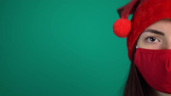 Portrait of Young Woman with Red Medical Face Mask and Santa Hat, Looking at Camera alt