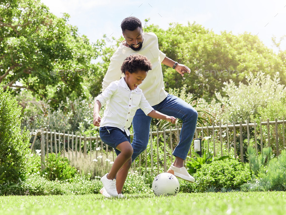 Playing like real football stars. Shot of a father and son playing soccer together outdoors.