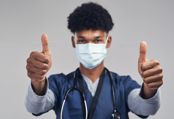 Youre making a difference. Shot of a male nurse showing thumbs up while wearing a surgical mask.
