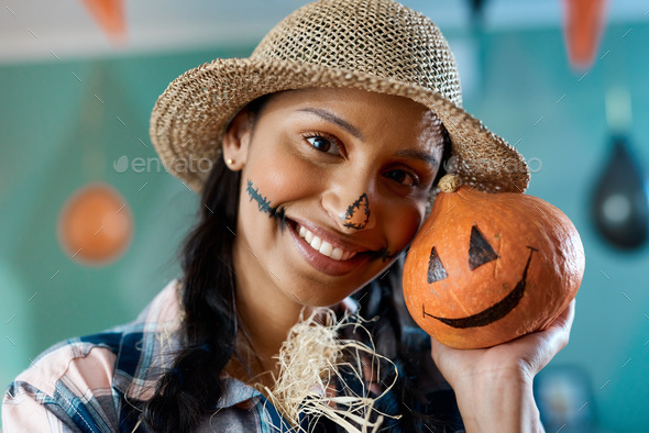 Say hi, pumpkin. Shot of a young woman holding a pumpkin at home.