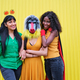 Three friends in Halloween costumes and accessories posing on a yellow background - PhotoDune Item for Sale