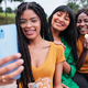 A young woman taking a selfie with her friends while eating potato chips in the park - PhotoDune Item for Sale