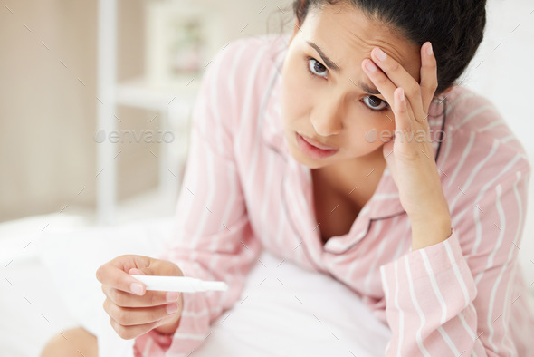 Im not ready for motherhood. Shot of a young woman looking stressed while holding a pregnancy test.