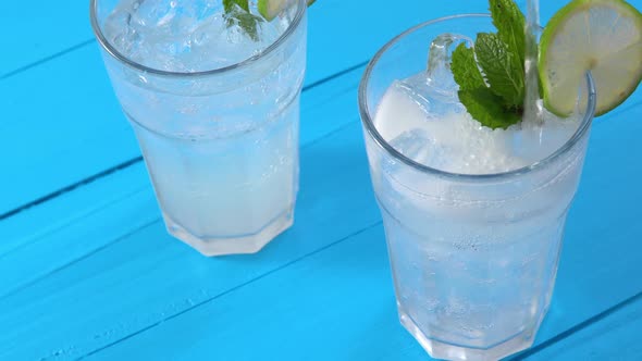 Glasses of fresh mojito cocktail with mint leaves and line slice on blue wooden table