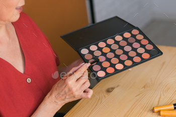 Close-up of woman holding makeup brush and blush and eyeshadow palette - beauty and cosmetics