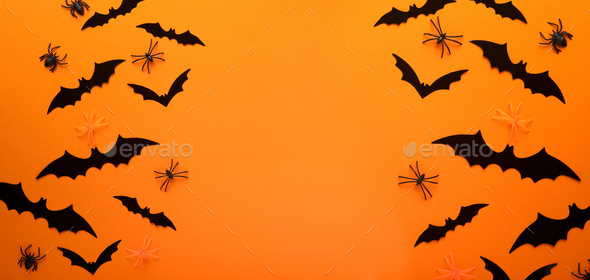 Orange Halloween background. Flock of black bats for Halloween. Black paper bat silhouettes