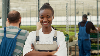 Portrait of woman posing smiling with arms crossed in organic vegetables farm with divers people