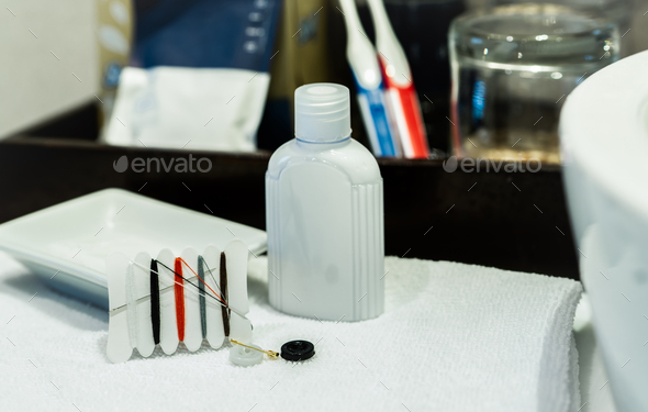 Hotel sewing kit and hand cream in hotel bathroom. Small portable thread repair emergency kit with