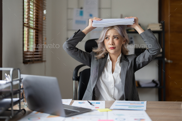 Portrait of beautiful asian woman at the desk with paperwork on her head. business overwhelmed