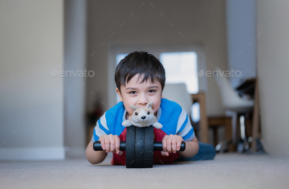 Happy young boy lying on floor playing roller wheel with dog toy,Kid with smiling face playing alone