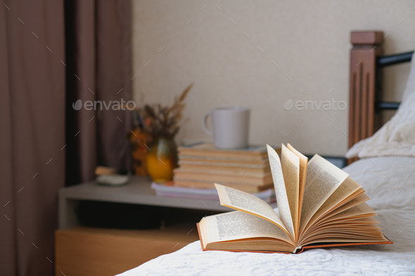 Old open book with yellow pages lies on a beige bed with pillows. Cozy fall mood in a room. - Stock Photo - Images