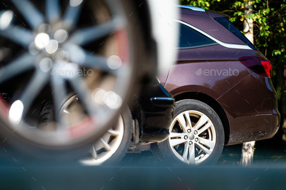 closeup of the wheels and bumpers of a car parked in the yard of a residential house, lower section