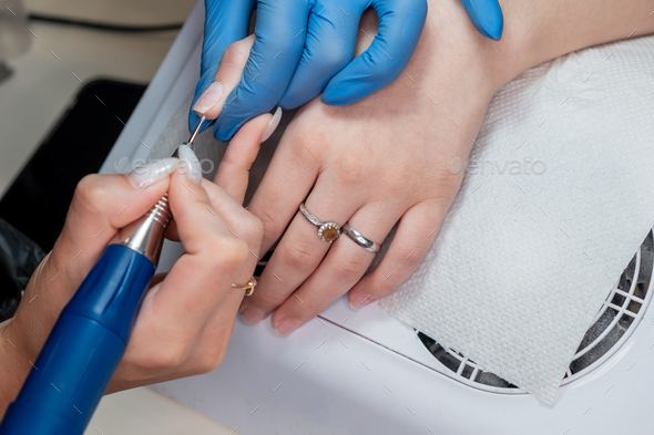 The manicurist cuts the cuticles with a sterile instrument