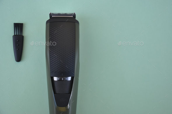 High angle shot of beard trimmer with comb and brush with negative space