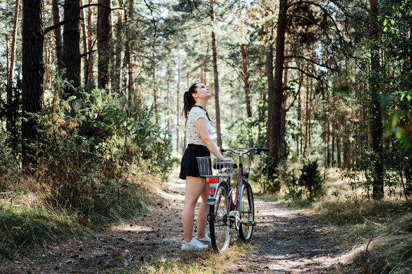Bicycle Tourism. Road Biking Trails. Bicycles for rent. Single woman riding bike in pine forest in