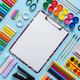 Colorful school supplies placed on blue background with white plain paper in the middle - PhotoDune Item for Sale