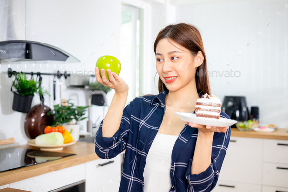 Asian healthy woman smiled and holding sweet and decide to chose apple fruit to eat clean food