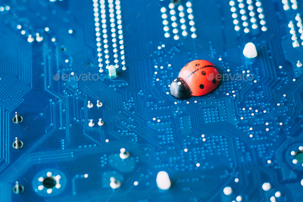Little red ladybug on blue motherboard. Concept of computer virus or bug, system failure