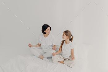 Indoor shot of happy mom and daughter have pleasant talk together, have yoga practice