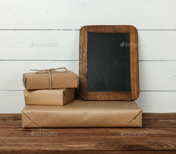 Stack of wrapped gifts and chalkboard on table