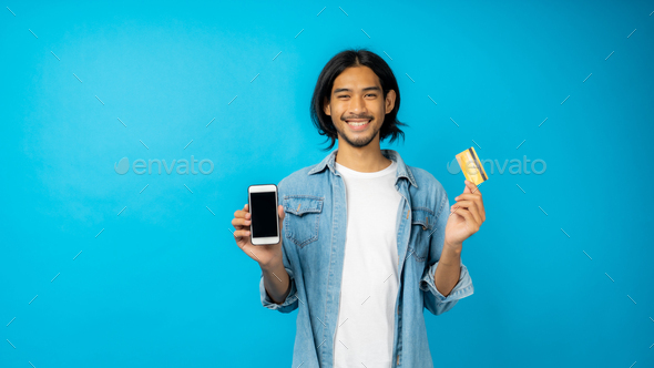 Asian Thai man with long hear and mustache holding phone and credit card, shopping online concept