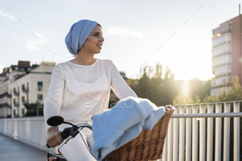 Muslim woman riding her bicycle on the sidewalk looking away
