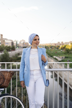 Portrait of a muslim woman standing with her purse on a footbridge looking at camera